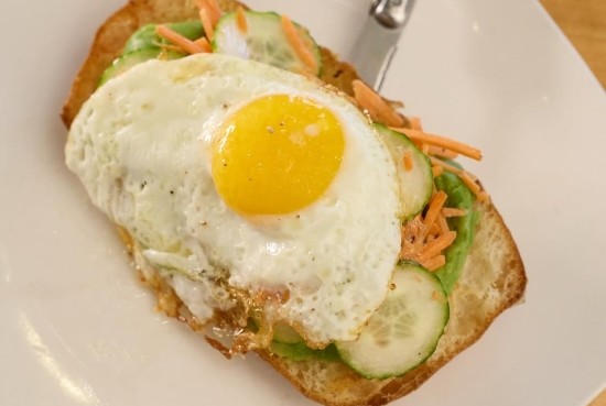 Fresh ciabatta toast topped with cucumber salad, avocado, and a sunny-side-up egg at Taste of Belgium.