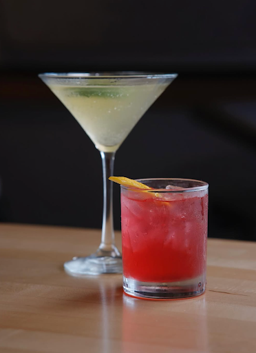 Two signature cocktails, Bee’s Knees and Martini, on the bar counter at Taste of Belgium in Cincinnati.