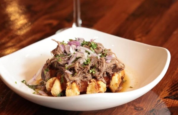 Pulled beef and crispy waffle bites garnished with red onions and herbs in a white bowl at Taste of Belgium.
