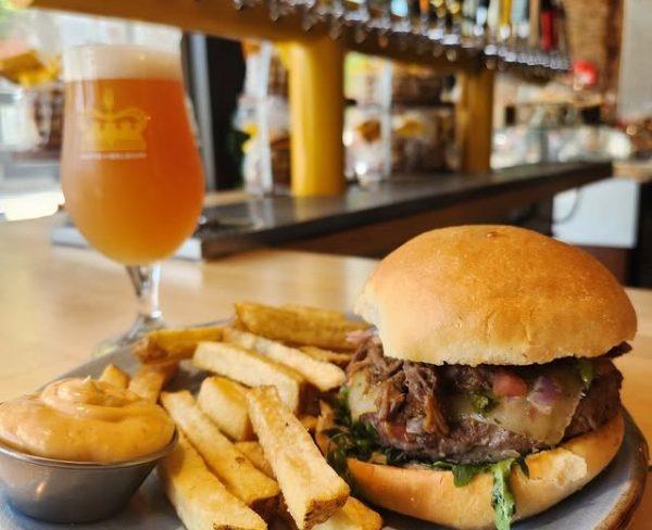 Beef sandwich with fries, dipping sauce, and a Belgian beer served at Taste of Belgium, with tap handles in the background.