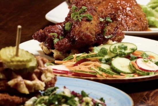 A plate of crispy chicken and waffles with a side salad served at Taste of Belgium in OTR Cincinnati.