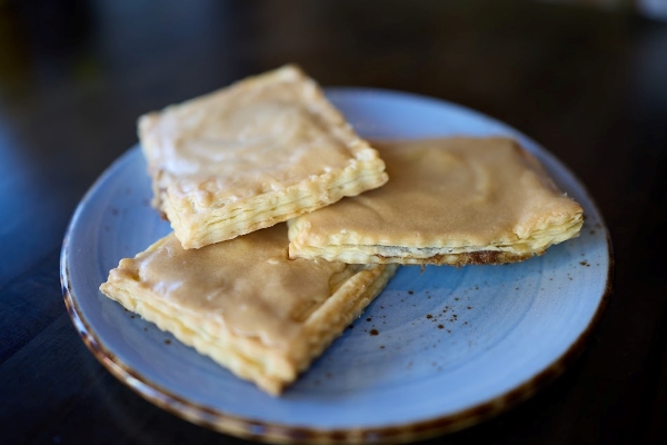 A plate of Belgian Tarte à Sucre pastries with brown sugar filling and golden sugar icing.