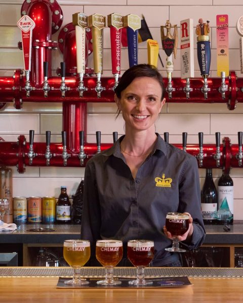 A lady enjoying a cold beer at The Banks branch of Taste of Belgium, featuring over 50 Belgian beers on draft, including Chimay.