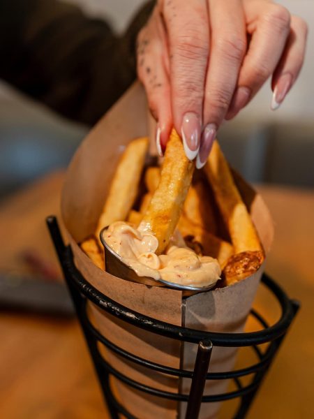 Woman picking up Belgian frites with dips from a tray at Taste of Belgium during a date night.