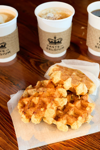 Trio of Liège waffles and hot coffee on a rustic wooden table at Taste of Belgium in Cincinnati.