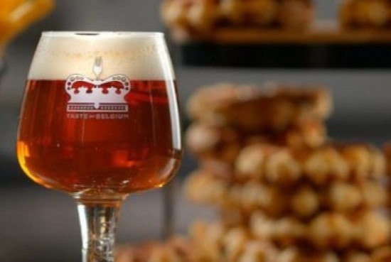Belgian beer in Taste of Belgium goblet with foamy head, served alongside golden waffles and crispy fries in Cincinnati.