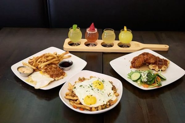 A high-angle view of a table with Belgian dishes, including waffles, eggs, and chicken, accompanied by mimosas at Taste of Belgium.