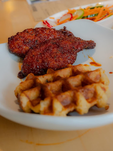 A combination of waffle and fried chicken served with salad.
